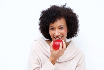 woman with dental implants in Temple biting into red apple 