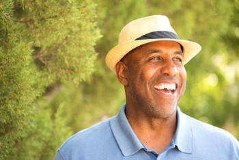 smiling man with dentures in Temple standing in front of trees