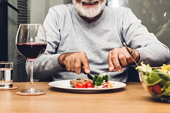 a man with dentures eating a delicious meal