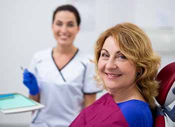 Older woman smiling with an emergency dentist in Temple