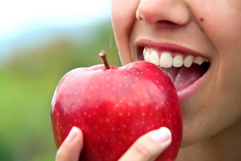 Woman with dental implants in Temple, TX about to bite into an apple