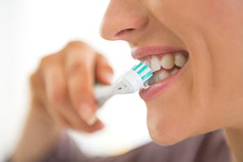 Woman with dental implants in Temple, TX brushing her teeth
