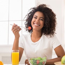 woman sitting at table eating salad 