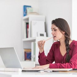 woman sitting at desk and chewing on pencil