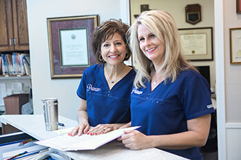Two smiling dental team members reviewing dental crown and bridge treatment plan
