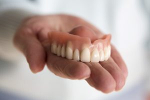 Hand holding dentures in Temple