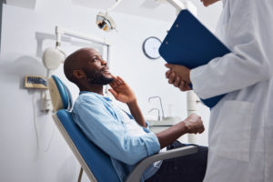 patient sitting in a dental chair and speaking with their dentist during a dental implant consultation